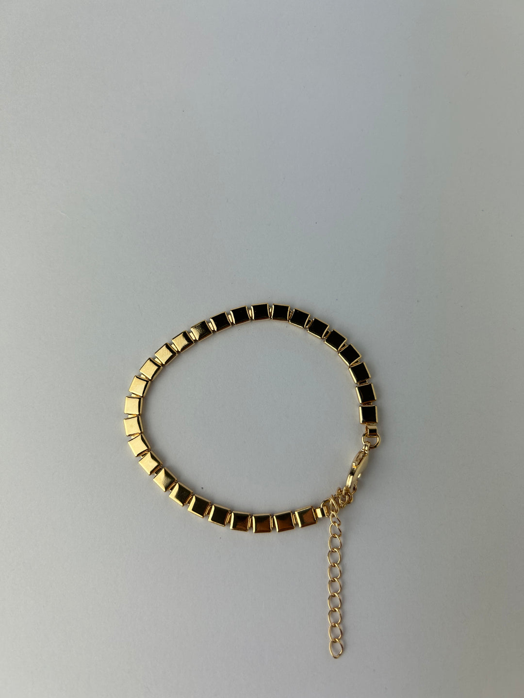 A gold-plated mini square bracelet with link chain design on a white background