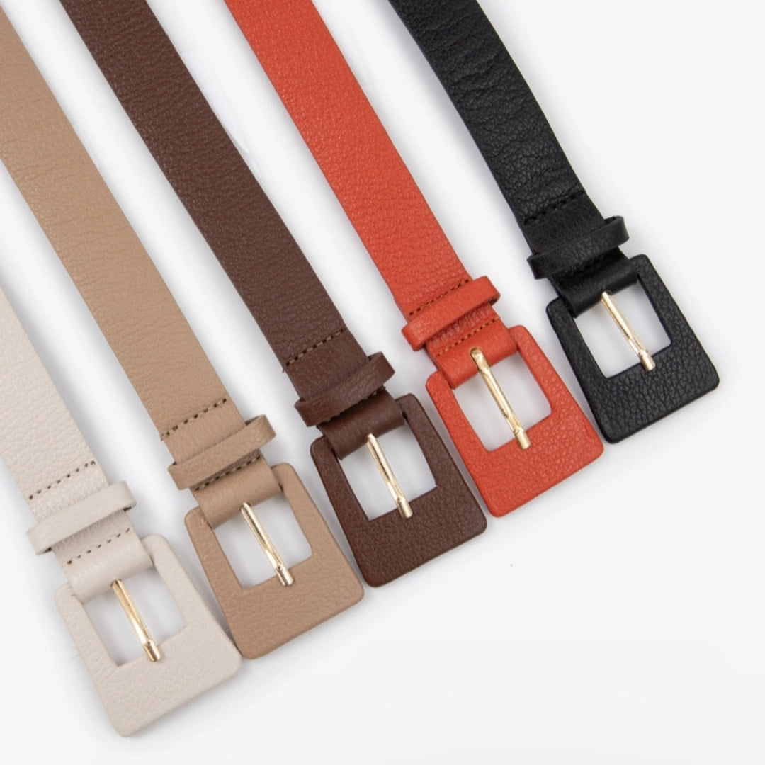 A collection of four rectangular leather belts in beige, black, brown, and red colors, all with metal buckles.