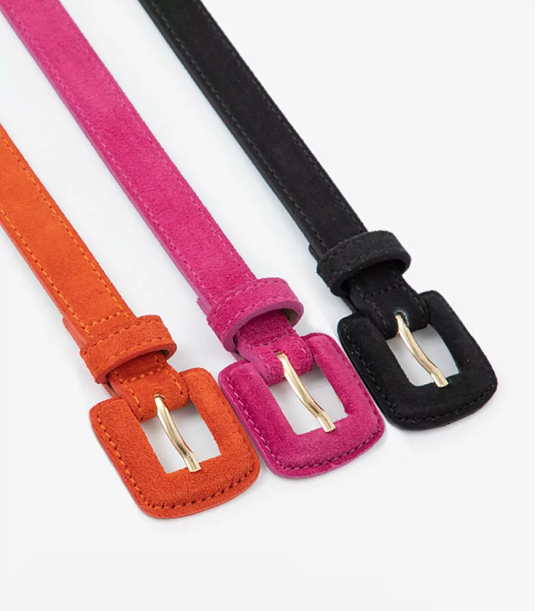 Two suede leather belts with metal buckles, one in pink and the other in black, positioned side by side.